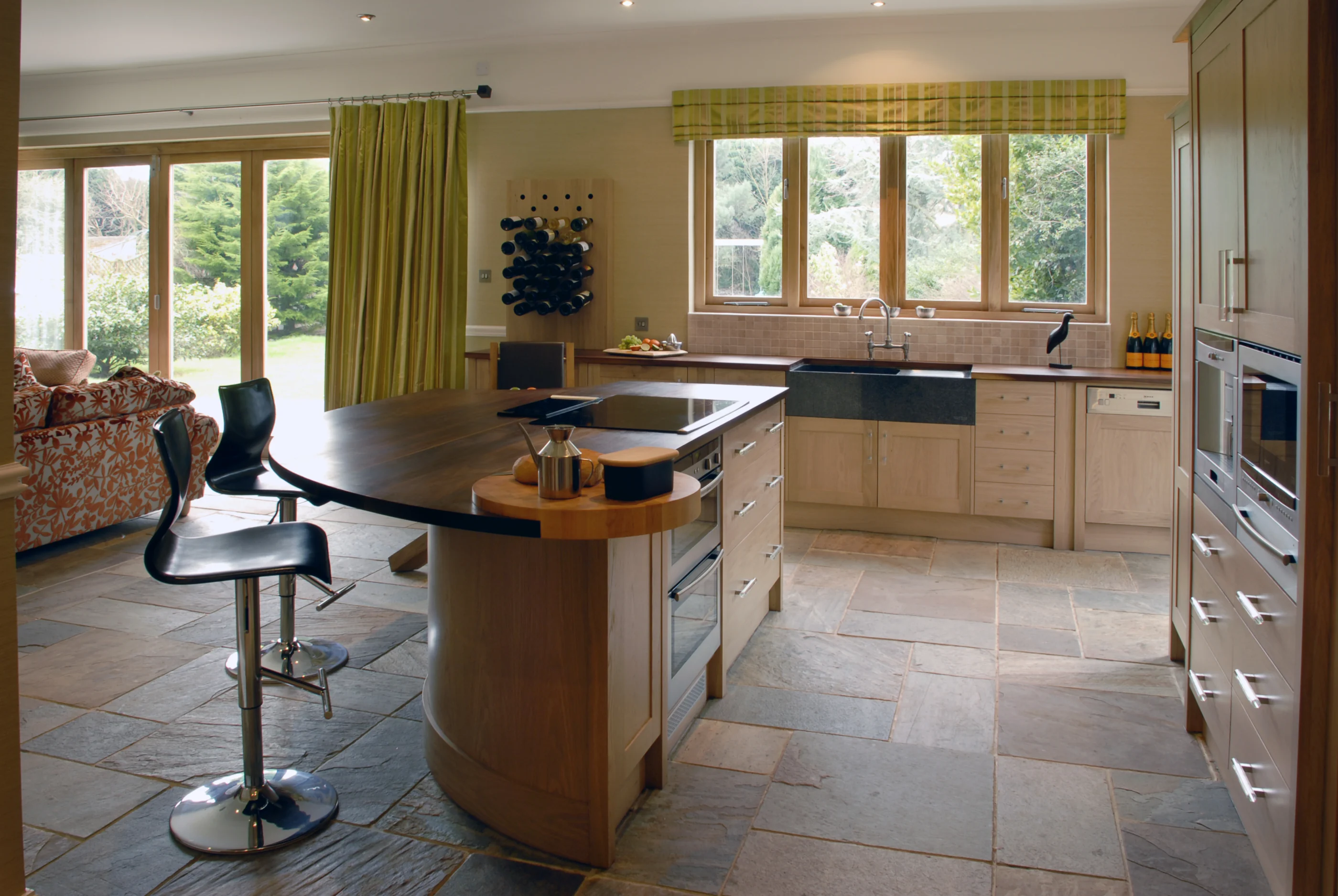 An oak kitchen arranged around a central island in a light open-plan room