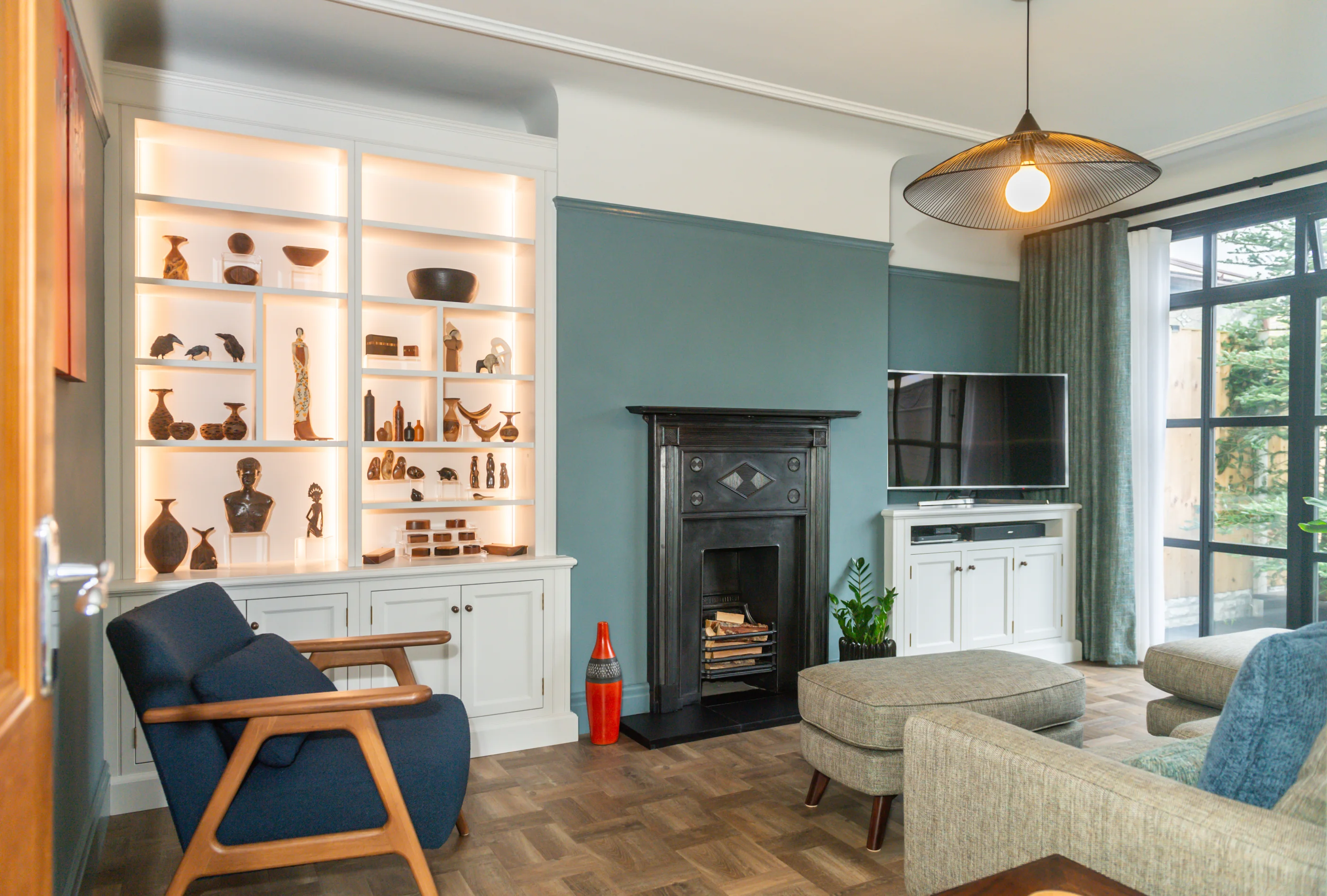 A sitting room with illuminated cabinetry fitted beside a fireplace