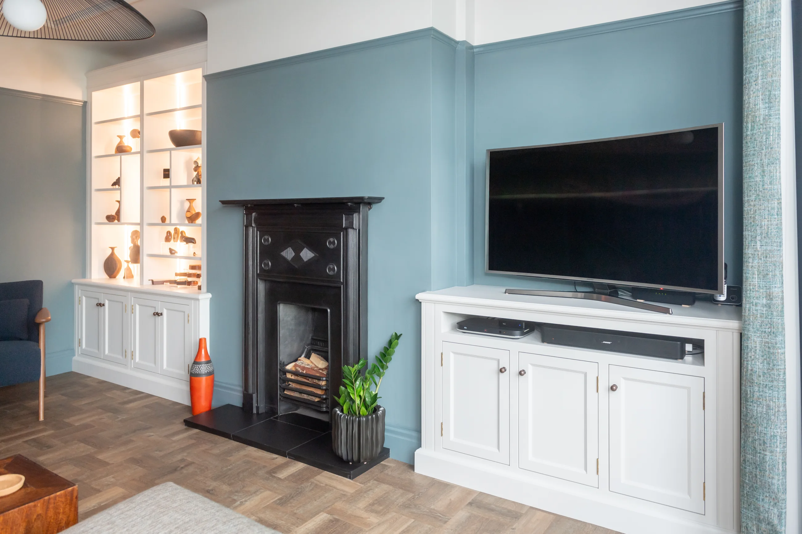 Pale fitted alcove cabinetry composed on both sides of a period fireplace
