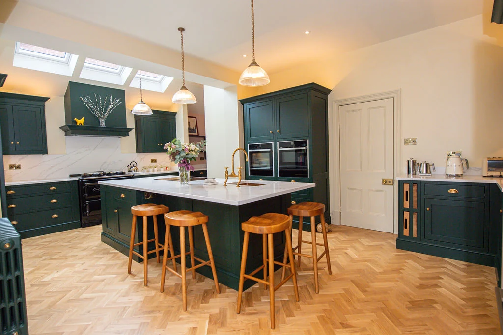 A complete green kitchen with a central island, range and fitted cabinetry